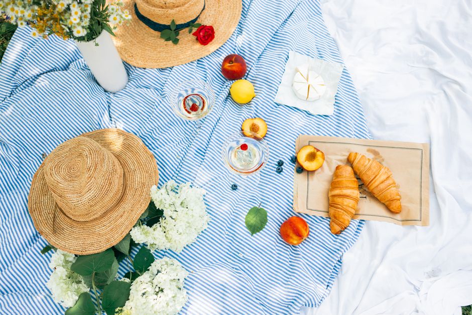 Picknickdeken met elegant servies en bloemen.