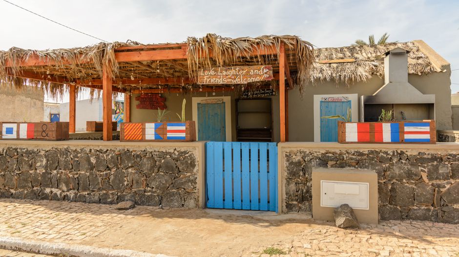 Kleurrijke kussens en schelpenversiering strandhuis chic.